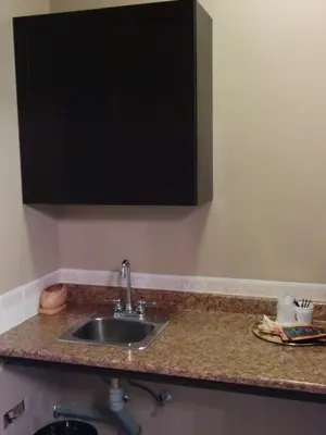 a kitchen counter with a sink and a cabinet at Bonnyville Hotel in Bonnyville