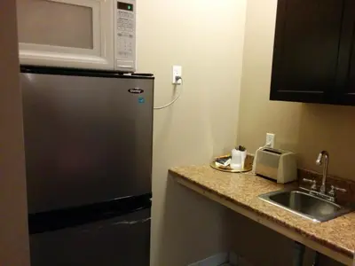 a kitchen with a refrigerator and a microwave at Bonnyville Hotel in Bonnyville