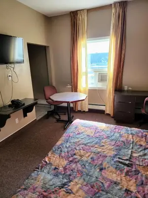 a hotel room with a table and a window at Bonnyville Hotel in Bonnyville