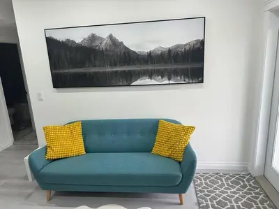 a blue couch with two yellow pillows in a room at Award winning boho paradise sunlit modern suite in Calgary