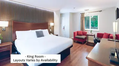 a hotel room with a king bed and a desk at Gibsons Garden Hotel in Gibsons