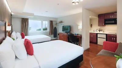 a hotel room with two beds and a kitchen at Gibsons Garden Hotel in Gibsons