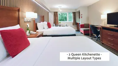 a hotel room with two beds and a desk at Gibsons Garden Hotel in Gibsons