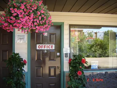 an office sign on a door with pink flowers at Hoo-Doo Motel in Drumheller