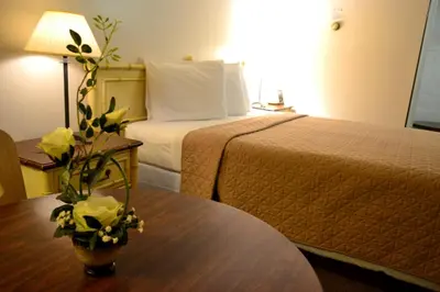 a hotel room with a bed and a table with flowers at Hoo-Doo Motel in Drumheller