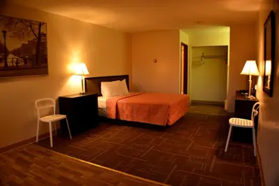 a hotel room with a bed and two chairs at Hoo-Doo Motel in Drumheller