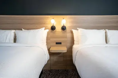 two beds in a hotel room with white pillows at Northwinds Hotel Revelstoke in Revelstoke