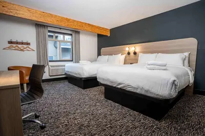 a hotel room with a large bed and a desk at Northwinds Hotel Revelstoke in Revelstoke