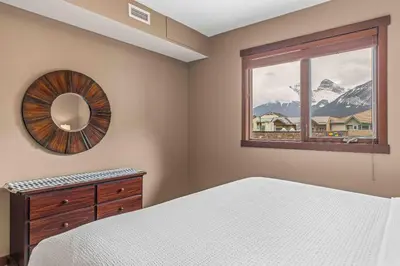 a bedroom with a bed and a mirror and a window at Best Views of Canmore - 2Bed 2Bath in Canmore