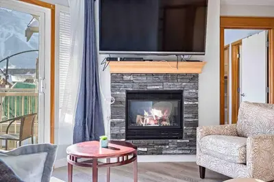 a living room with a fireplace with a tv above it at Lux 2BR 5BD Suite Mountain view! in Canmore