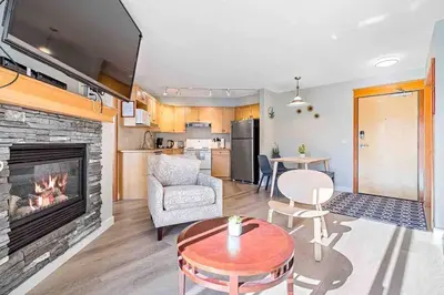 a living room with a fireplace and a kitchen at Lux 2BR 5BD Suite Mountain view! in Canmore