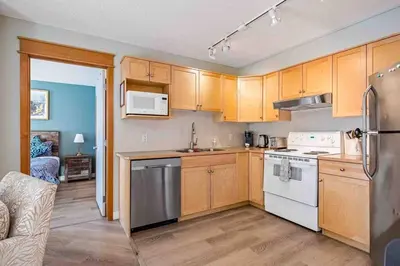 a kitchen with wooden cabinets and white appliances at Lux 2BR 5BD Suite Mountain view! in Canmore