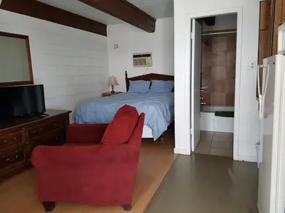 a bedroom with a bed and a red chair at Caravan Motel in Fort Saint John