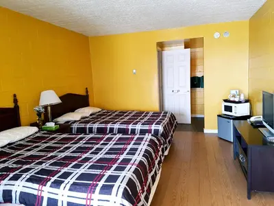 a hotel room with two beds and a tv at Caravan Motel in Fort Saint John