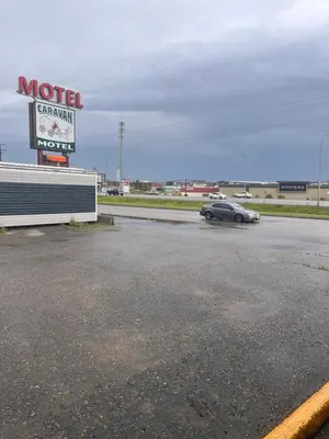 a car parked in a parking lot with a motel sign at Caravan Motel in Fort Saint John
