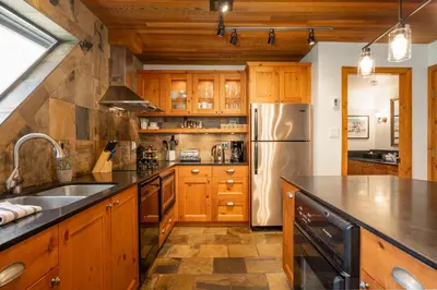 a kitchen with wooden cabinets and a stainless steel refrigerator at 3BR in Snowberry, King Bed, Wood Burning Fireplace, Large Kitchen, Near Gondola in Whistler