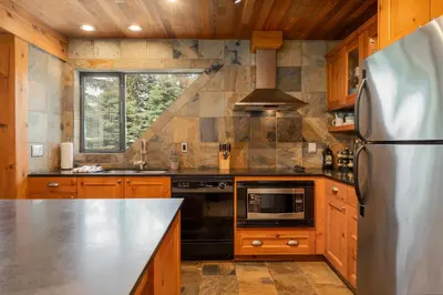 a kitchen with wooden cabinets and a stainless steel refrigerator at 3BR in Snowberry, King Bed, Wood Burning Fireplace, Large Kitchen, Near Gondola in Whistler