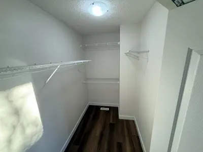 a walk in closet with white walls and wooden floors at Spacious & Private Retreat near West Edmonton Mall in Edmonton