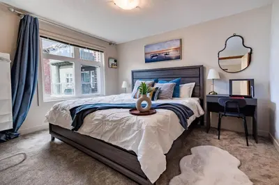a bedroom with a bed and a desk and a window at Lux 2BR/3BD Suite/Mountain View! in Canmore