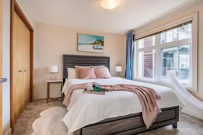 a bedroom with a large bed and a window at Lux 2BR/3BD Suite/Mountain View! in Canmore