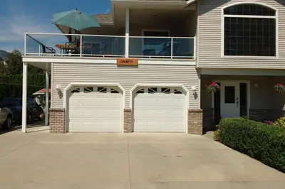 a house with two garage doors and a balcony with an umbrella at Grumpy's Suite by the Lake in Summerland
