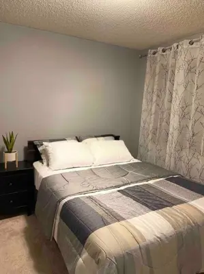 a bedroom with a bed in a room with a curtain at Spacious, 2-story Family-Friendly home in Calgary