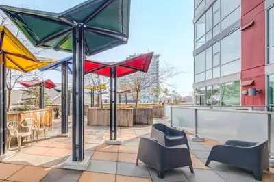 a patio with chairs and umbrellas on a building at Modern Condo w Balcony - Steps from Stampede Park in Calgary