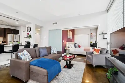 a living room with a couch and a kitchen at Modern Condo w Balcony - Steps from Stampede Park in Calgary