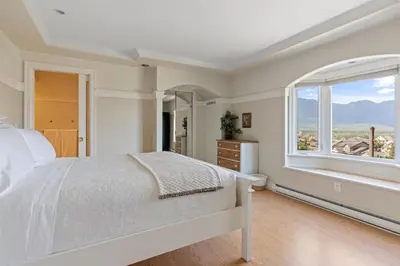 a bedroom with a bed and a large window at Grand English Style Home in Chilliwack