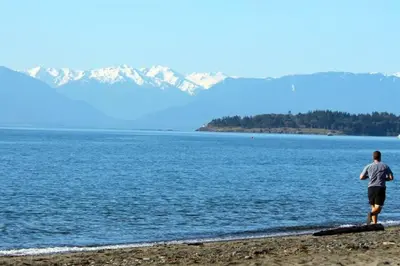 a man standing on the beach looking at the water at The Royal Bay Escape: Cozy 2 bedrooms garden suite in Colwood
