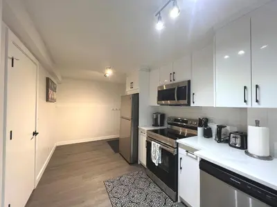 a kitchen with white cabinets and black appliances at Cozy 3 beds Suite Near Calgary Airport Sleeps 6 in Calgary