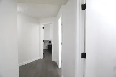 an empty hallway with white walls and wood floors at Cozy 3 beds Suite Near Calgary Airport Sleeps 6 in Calgary