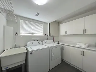 a white laundry room with two washes and a sink at Cozy 3 beds Suite Near Calgary Airport Sleeps 6 in Calgary