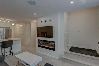 a living room with a fireplace and a kitchen at Cozy New Suite in Seton, South Calgary in Calgary