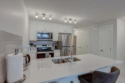 a white kitchen with a sink and a refrigerator at Cozy New Suite in Seton, South Calgary in Calgary
