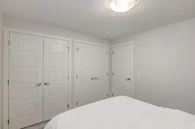 a bedroom with white cabinets and a bed at Cozy New Suite in Seton, South Calgary in Calgary