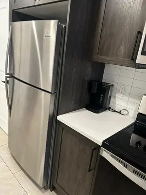 a kitchen with a stainless steel refrigerator and wooden cabinets at Praise bethel -Homely walkout legal basement in YYC in Calgary