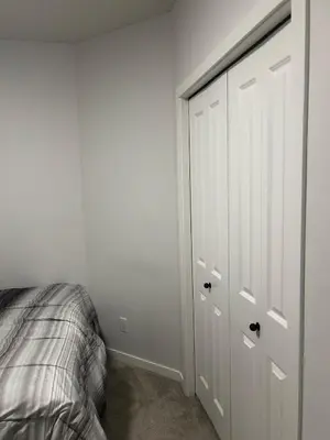 a white bedroom with a bed and a closet at Praise bethel -Homely walkout legal basement in YYC in Calgary