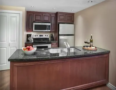 a kitchen with wooden cabinets and a counter top with a sink at Residences at the Sun Peaks Grand in Sun Peaks