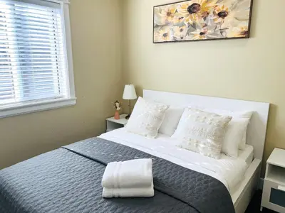 a bedroom with a white bed with pillows and a window at Jennifer's House in Vancouver