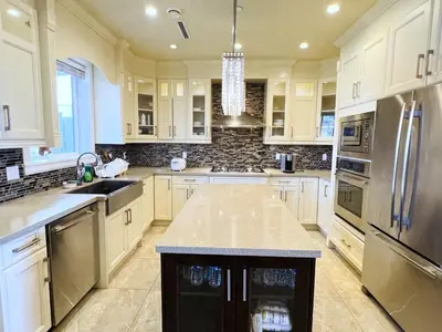 a kitchen with white cabinets and stainless steel appliances at Jennifer's House in Vancouver