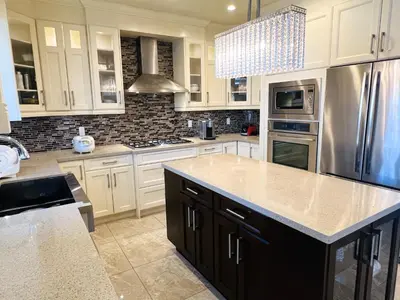 a kitchen with white cabinets and a stainless steel refrigerator at Jennifer's House in Vancouver