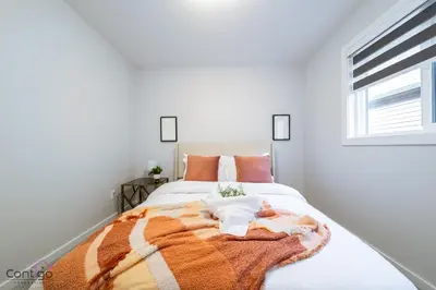 a bedroom with a bed with an orange and white blanket at Orchards Retreat, AC, Family Friendly, Sleeps 10, NearAirprt in Nisku