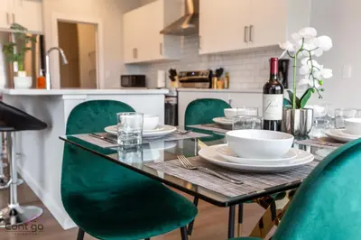 a dining table with green chairs and a bottle of wine at Orchards Retreat, AC, Family Friendly, Sleeps 10, NearAirprt in Nisku