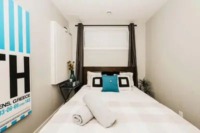 a small bedroom with a bed with two pillows at Modern suite near Airport Hospital Henday Town Ctr in Nisku
