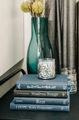 a stack of books sitting on a table with a vase at Modern suite near Airport Hospital Henday Town Ctr in Nisku