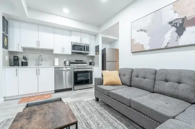 a living room with a couch and a kitchen at Stylish Getaway 2BD Basement by YMCA and South Health Campus Hospital in Calgary