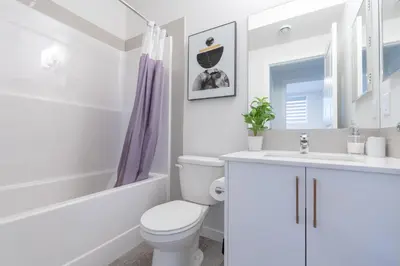 a white bathroom with a toilet and a sink at Stylish Getaway 2BD Basement by YMCA and South Health Campus Hospital in Calgary
