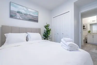 a white bedroom with a large white bed with white pillows at Stylish Getaway 2BD Basement by YMCA and South Health Campus Hospital in Calgary