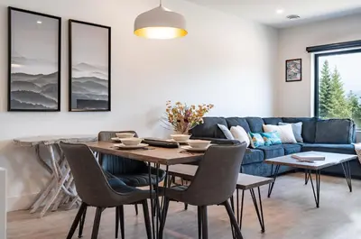 a living room with a table and a blue couch at Slopes and Greens by Revelstoke Vacations in Revelstoke